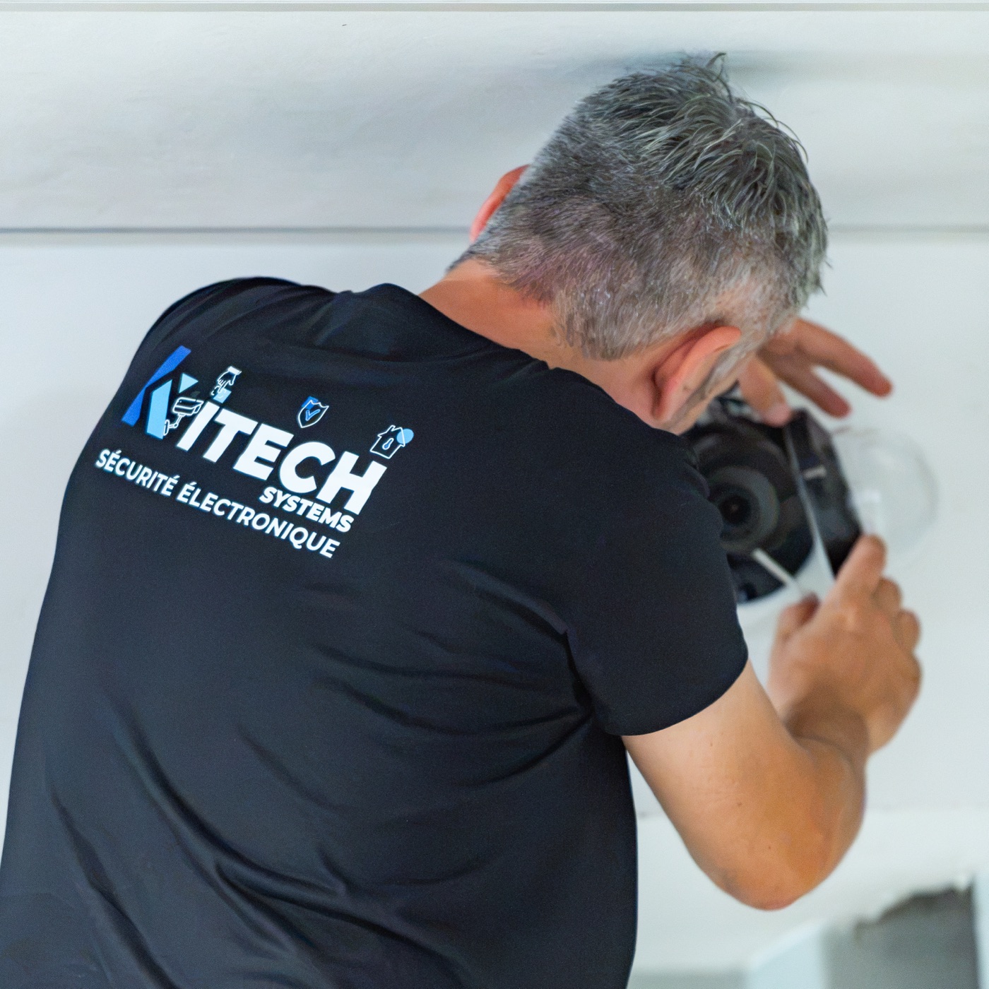 Technicien Kitech installant une caméra dôme dans un commerce de proximité